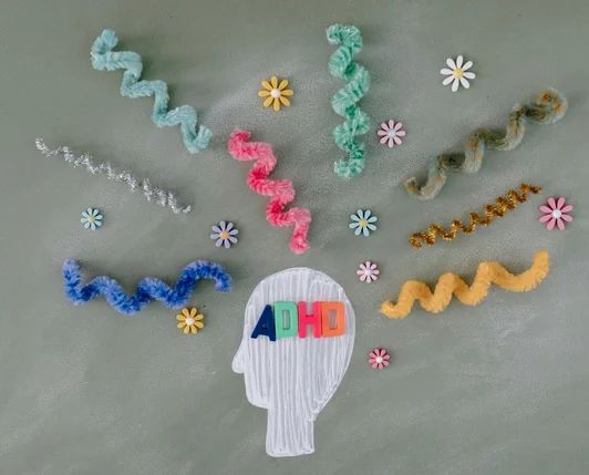 Silueta de una cabeza con la palabra ADHD y espirales de colores